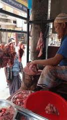 Butcher cuts meat at outdoor Dhaka market stall