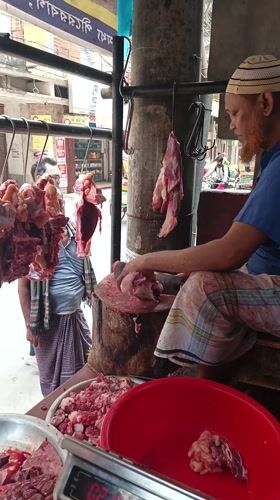 Butcher cuts meat at outdoor Dhaka market stall