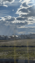 Rural Russian landscape captured from moving vehicle under cloudy sky