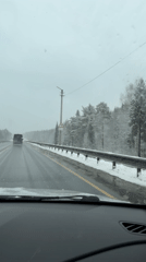 Vehicle travels snowy Russian highway in grey conditions