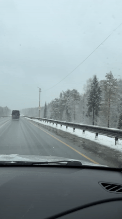 Vehicle travels snowy Russian highway in grey conditions