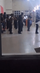 Group in dark uniforms rehearses or performs at indoor venue