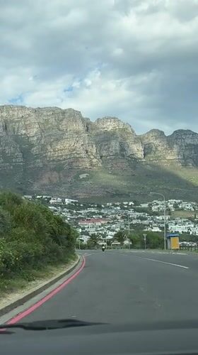 Driver travels Cape Town residential road with Table Mountain view