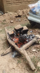 Coconuts roasting over a wood fire on a brick hearth in Lhokseumawe
