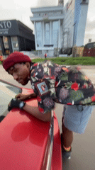 Rollerblade conversation leaning over a red car in Lagos