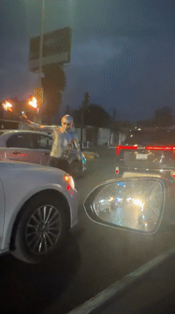 Silver-painted fire performer approaches cars in Cholula street