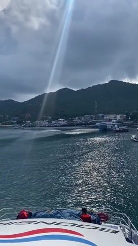 Boat passenger films sunlit Ko Tao coastline from water