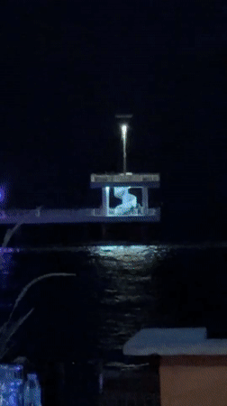 Nighttime waterfront gathering documented at illuminated pavilion and pier