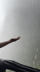 Person reaches hand into heavy rainfall during storm