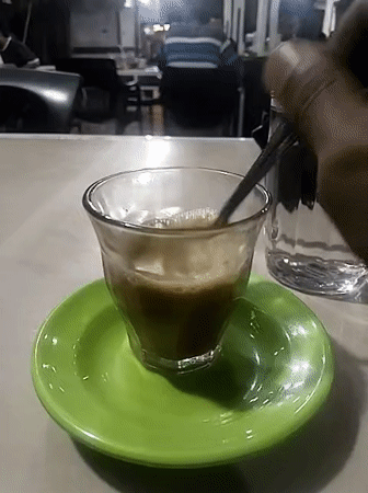 Coffee break captured at Lhokseumawe cafe with phone scrolling