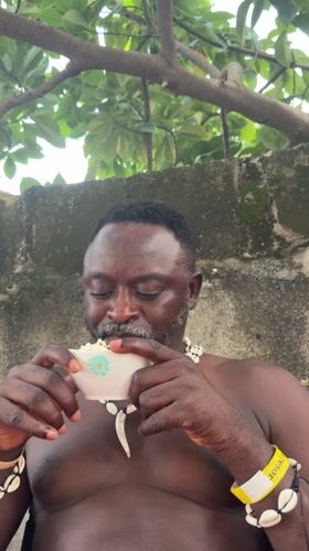 Man in shell jewelry enjoys popcorn across Nigerian locations