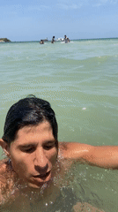 Man drinks from silver cup while standing in Venezuelan ocean