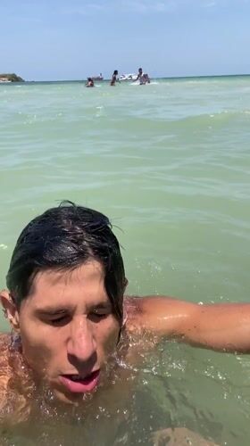Man drinks from silver cup while standing in Venezuelan ocean