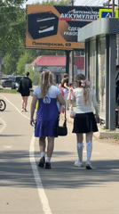Two women walk sunny sidewalk in Birobidzhan, Russia