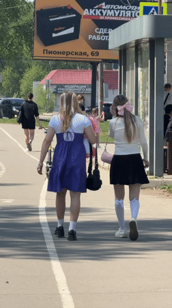 Two women walk sunny sidewalk in Birobidzhan, Russia