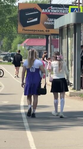 Two women walk sunny sidewalk in Birobidzhan, Russia