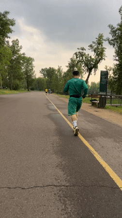 Runner in green tracksuit jogs through Krasnoyarsk park