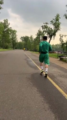 Runner in green tracksuit jogs through Krasnoyarsk park
