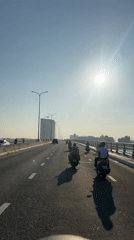 Motorcyclist records bridge traffic on sunny day in Vietnam