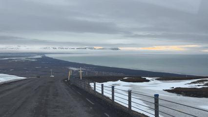 Traveler documents curved road overlooking Iceland coastal landscape