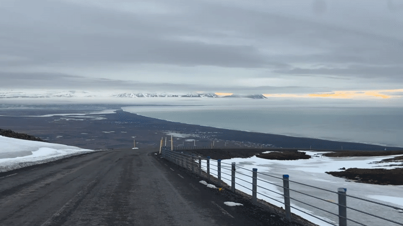Traveler documents curved road overlooking Iceland coastal landscape