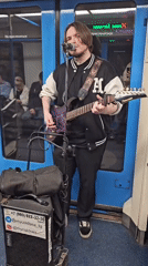 Musician performs in subway car aisle during morning commute