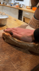 Person cuts bread on wooden board in Sandgate