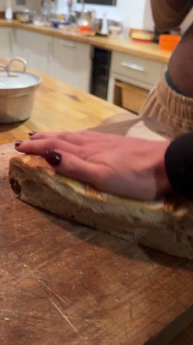 Person cuts bread on wooden board in Sandgate