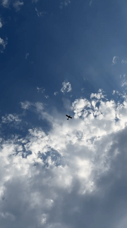 Small plane silhouetted against a sunlit sky over Wrocław
