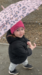 Girl with pink umbrella walks outdoor path in Izhevsk