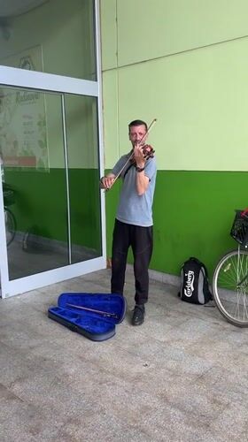 Street musician performs violin on Podgorica sidewalk