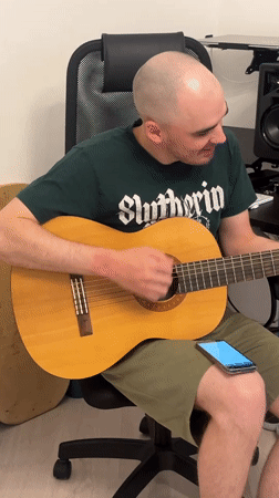 Man plays acoustic guitar in office chair in Yekaterinburg