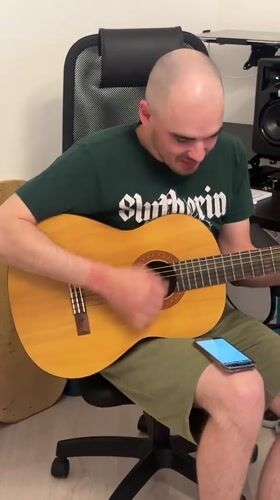 Man plays acoustic guitar in office chair in Yekaterinburg
