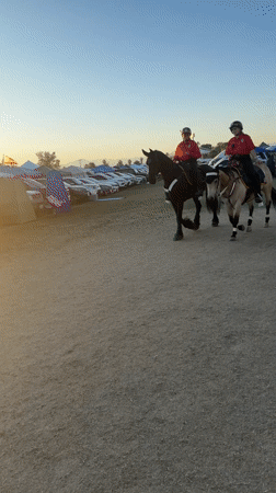 Mounted police patrol dusty Indio lot at sunset