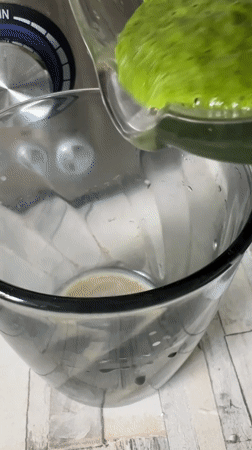 Bright green smoothie pours into a glass, close up.