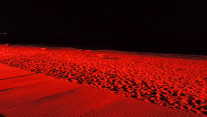 Red-lit outdoor event with tent, crowds observed in Varna