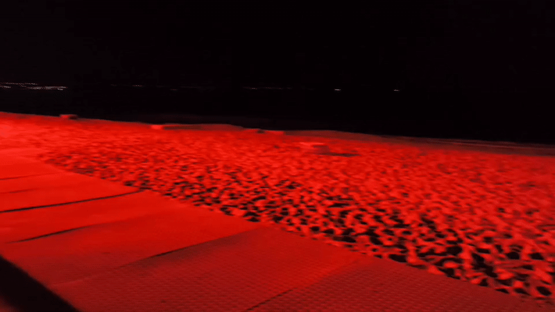 Red-lit outdoor event with tent, crowds observed in Varna