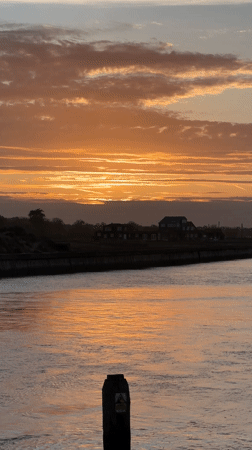 Colorful sunset captured over Suffolk waterway with floating object