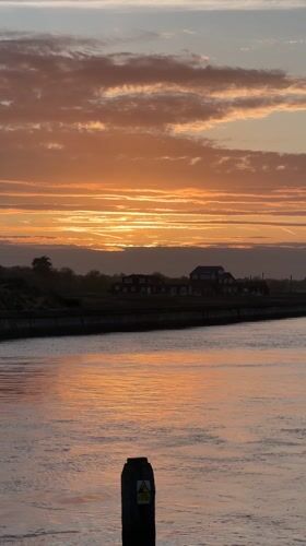 Colorful sunset captured over Suffolk waterway with floating object