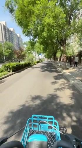 Cyclist rides tree-lined road in Changping District, China