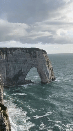 Woman poses at famous Étretat cliffs during evening photo session