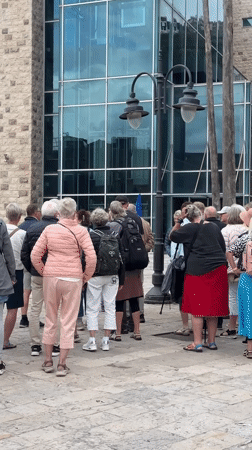Twenty older adults gather on cobblestone plaza in Budva
