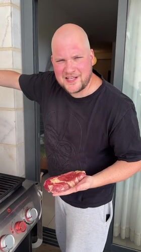 Man grills steaks on balcony in Ashkelon Friday afternoon