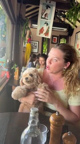 Woman shares breakfast with small dog at Indonesian cafe