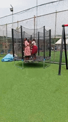 Children play at outdoor playground with trampolines and carousel