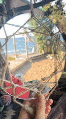 Rope-framed mirror reflects a beach scene at the shore