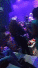 Indoor nightlife scene with dancing under purple and blue lights