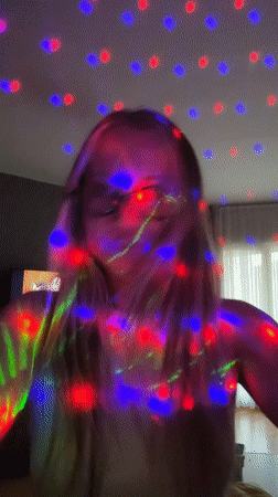 Girl dances enthusiastically in colorful lights in Esenyurt home