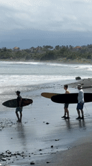 Surfers enter ocean at black sand beach