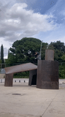 Scooter rider performs stunts on metal sculpture in Barcelona plaza